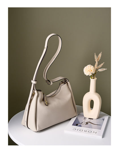 Off-white leather shoulder bag styled with vase and book on side table