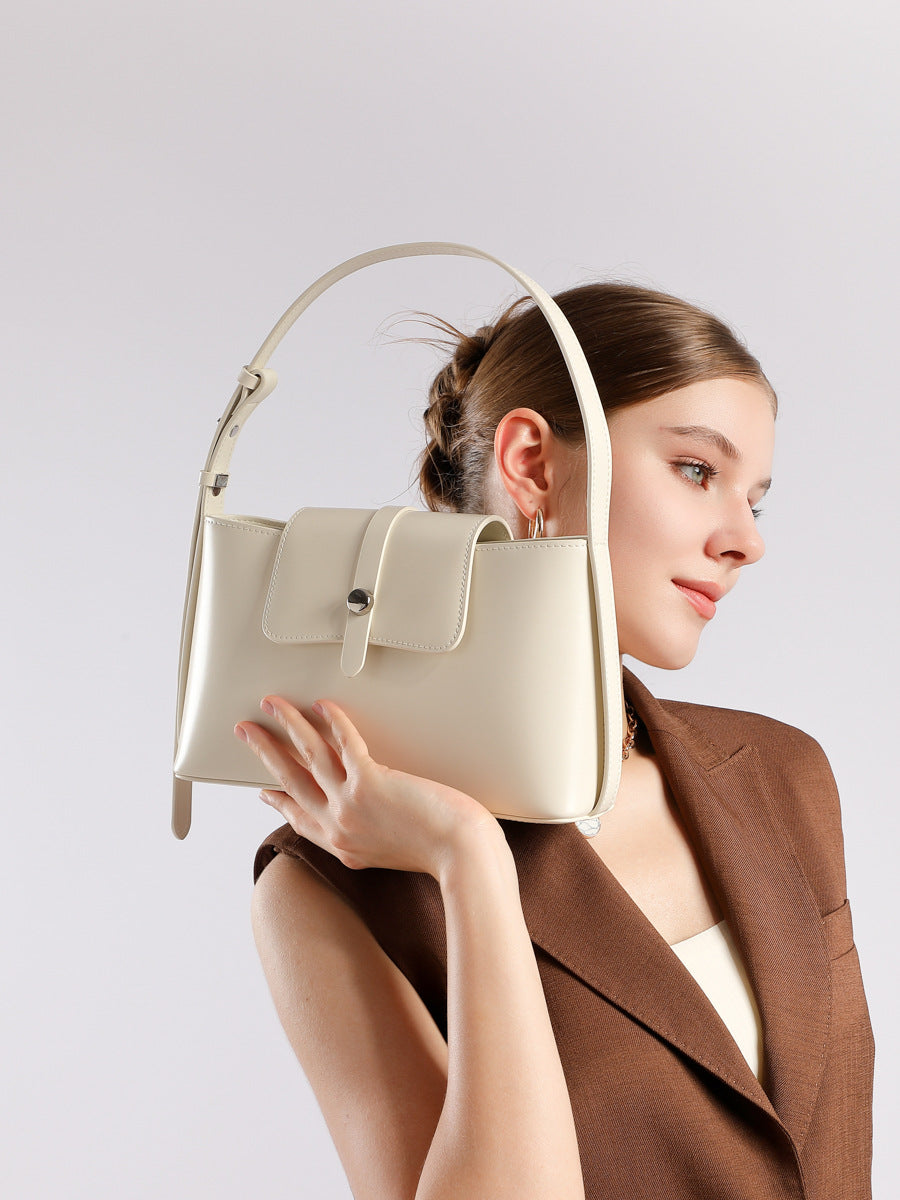 Model carrying white leather shoulder bag dressed in brown blazer