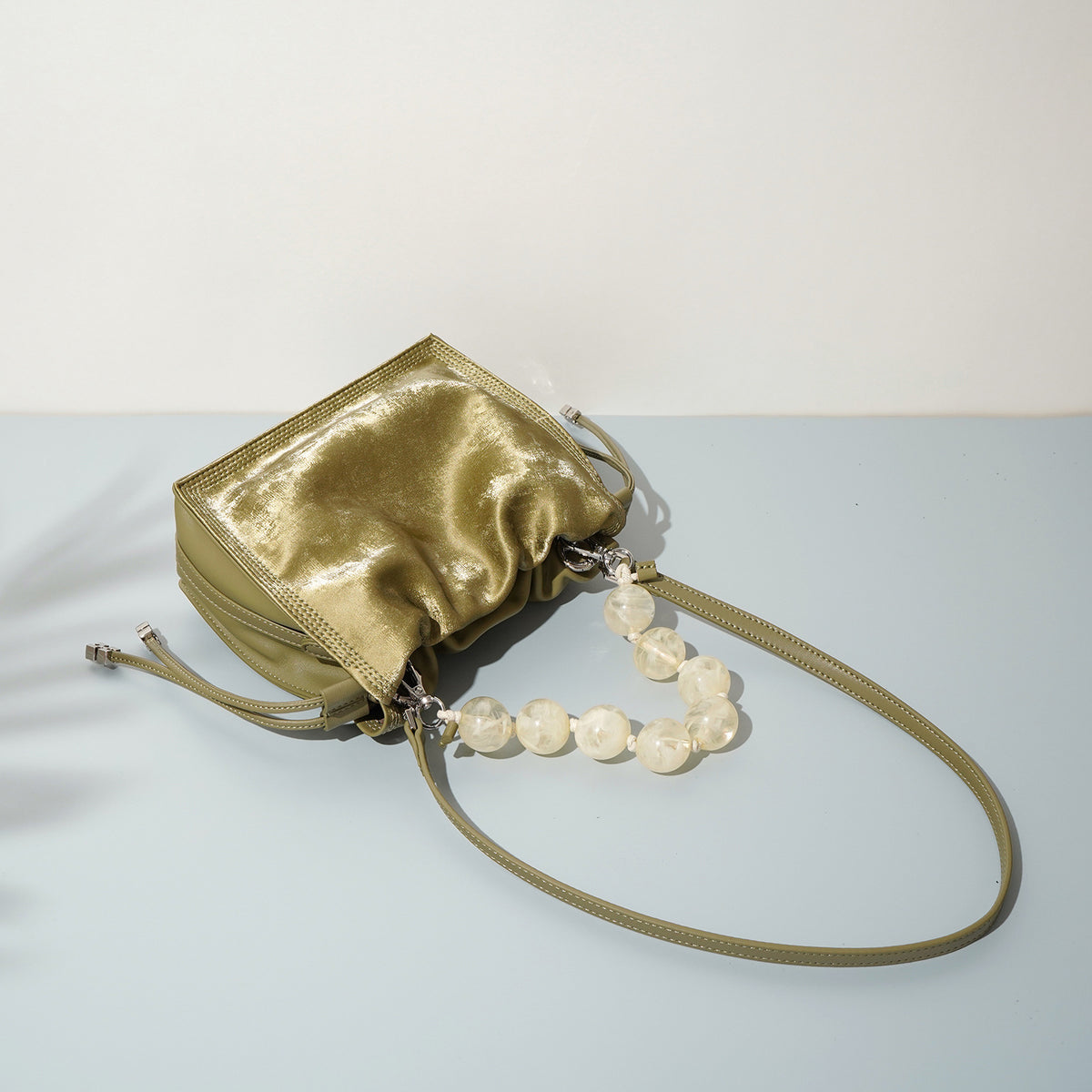 Top-down view of champagne mini bucket bag with beaded handle laid flat