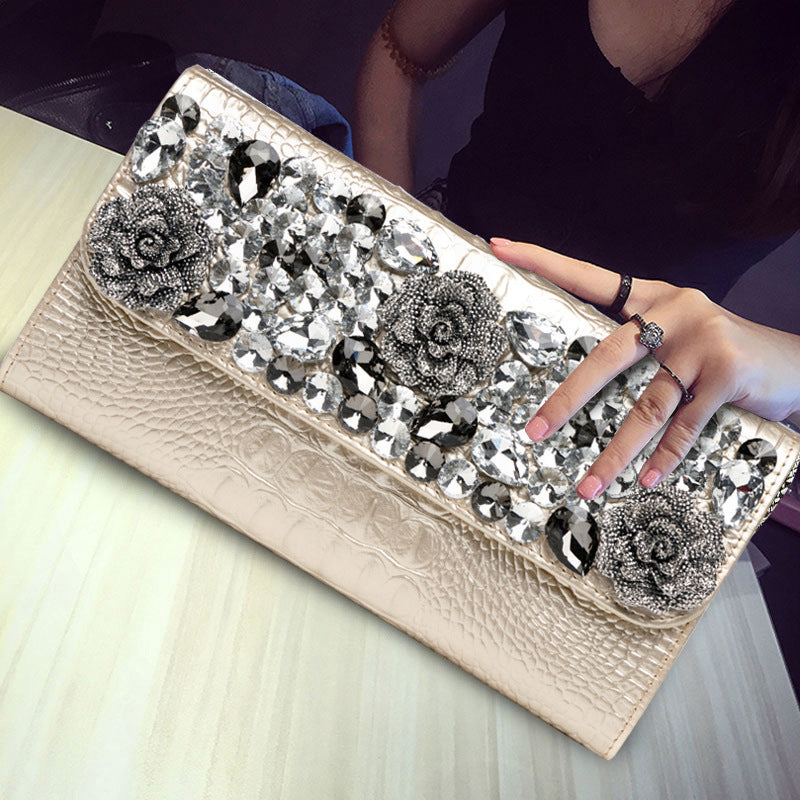 Light gold clutch with decorative stones and rose appliques displayed close up