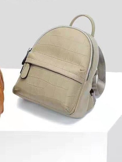 Gray mini backpack showing its rounded shape and front zip pocket