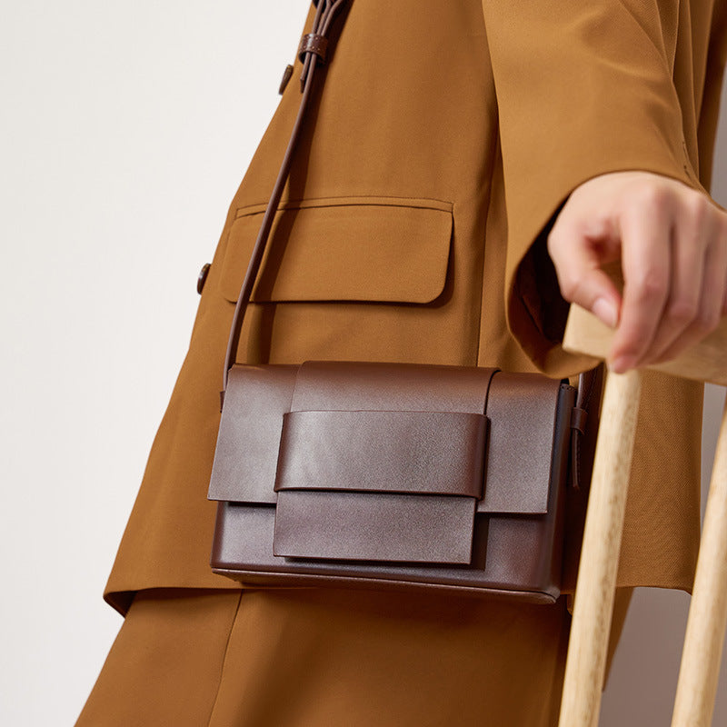 Coffee brown leather crossbody bag with bow flap styled with a tan coat