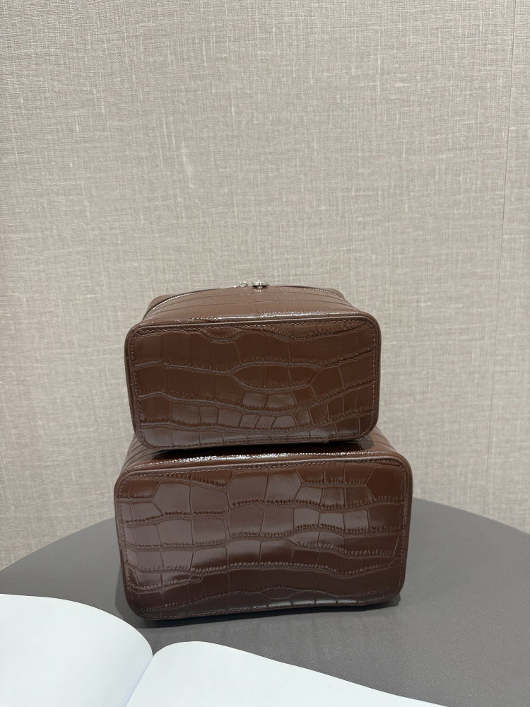 Rear view of two crocodile-embossed chocolate cosmetic pouches