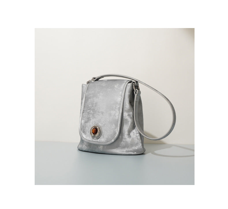 Silver gray split leather bucket bag angled side view on table