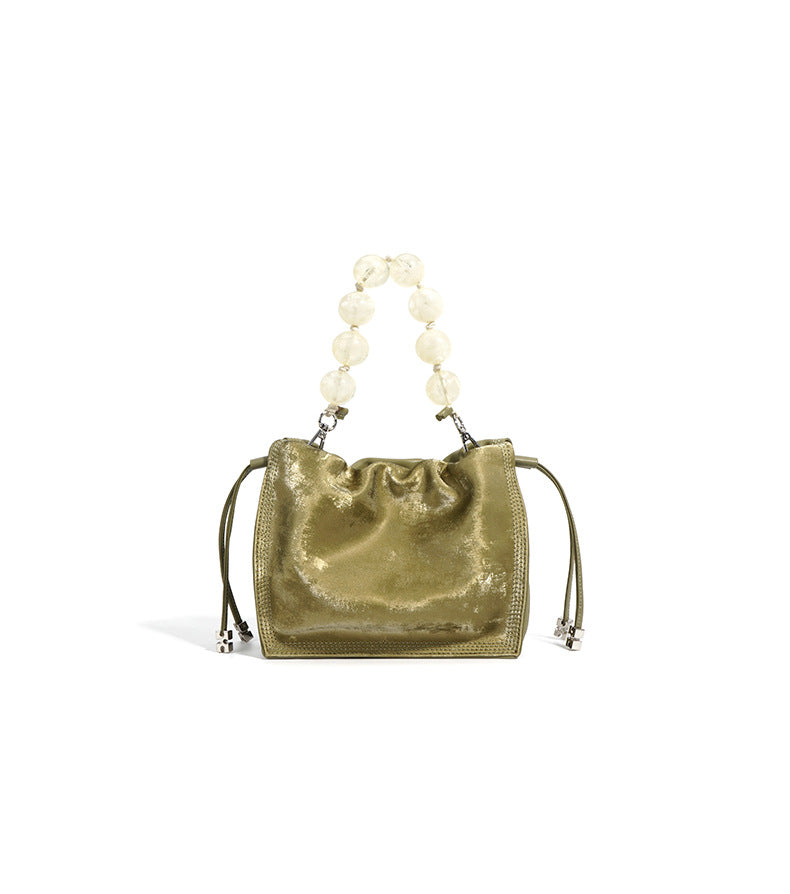 Alternate front view of champagne mini bucket bag with beaded handle raised