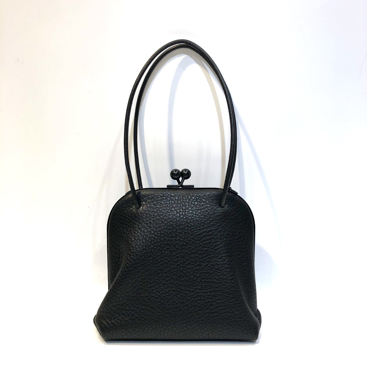 Black leather shoulder bag showing pebbled surface and clasp