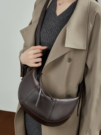 Coffee colored pebble leather hobo bag on shoulder with trench coat