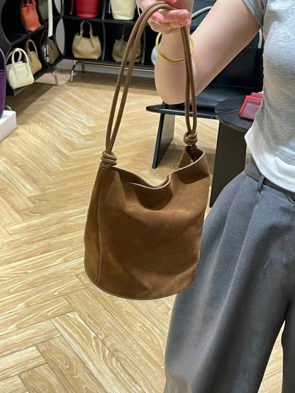 Brown bucket shoulder bag carried by its strap