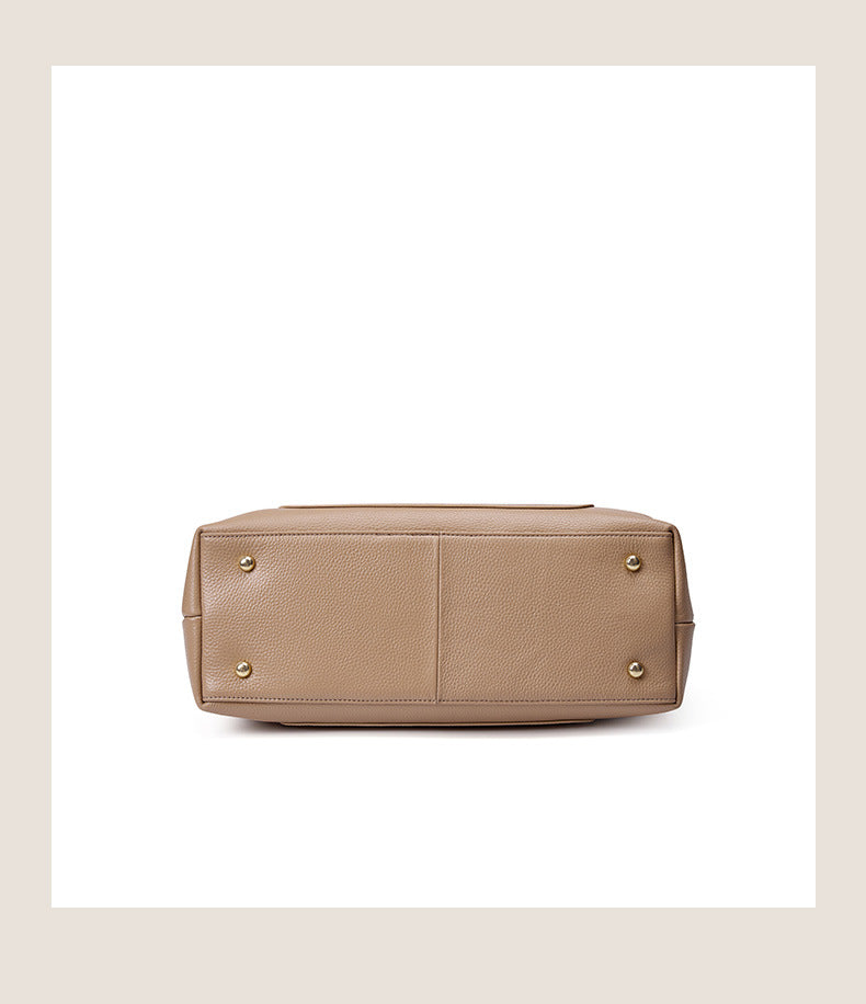 Bottom view of leather tote showing four protective metal feet