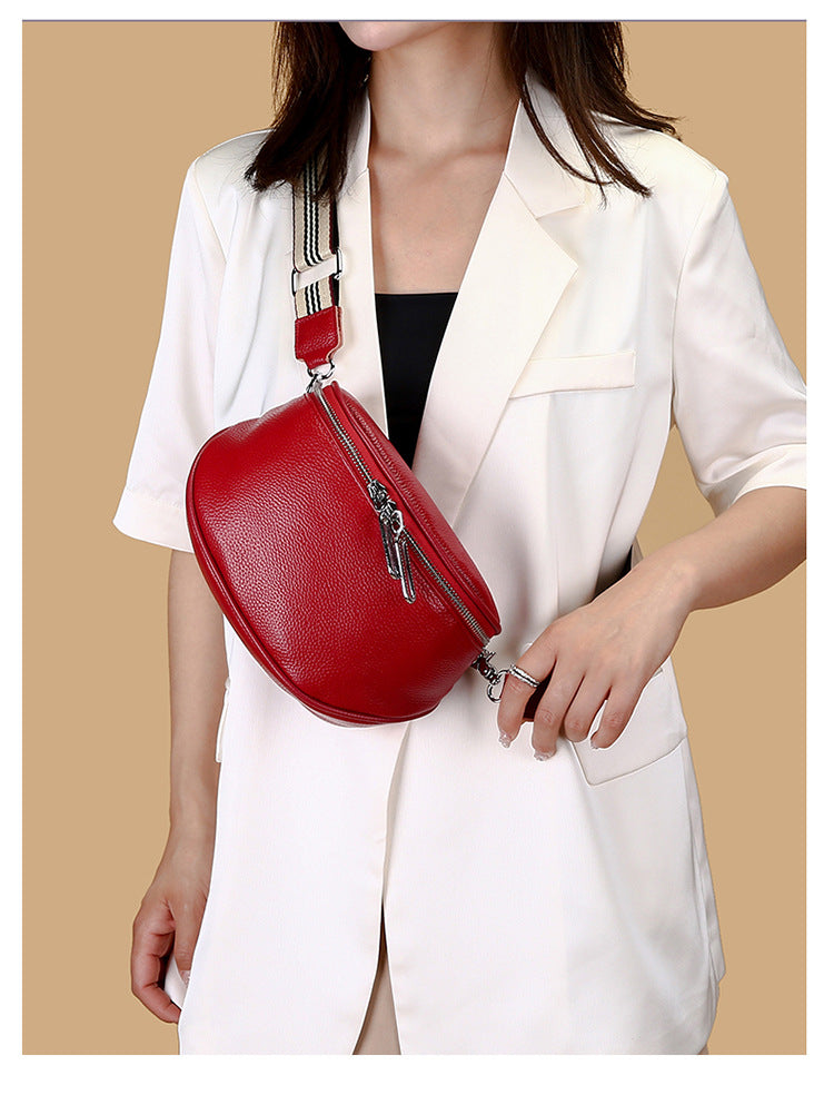 Red crossbody bag styled on a model with striped shoulder strap