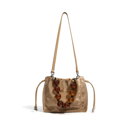 Champagne metallic cowhide mini bucket bag with beaded top handle on white background