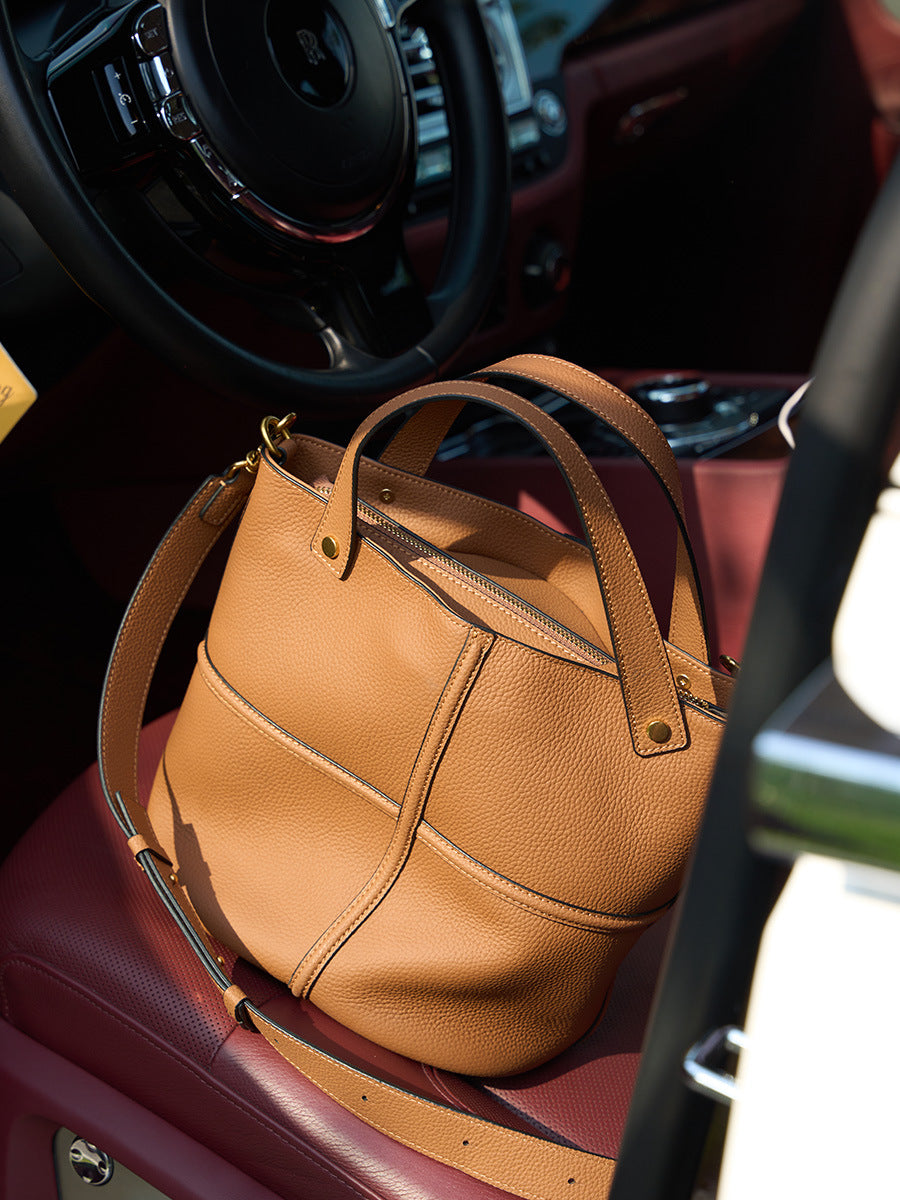 Brown leather bucket bag resting on a car seat