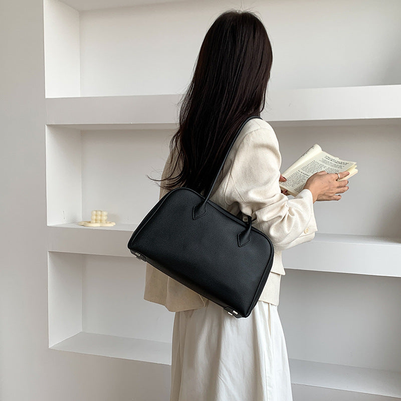 Black leather shoulder bag shown from the back while carried