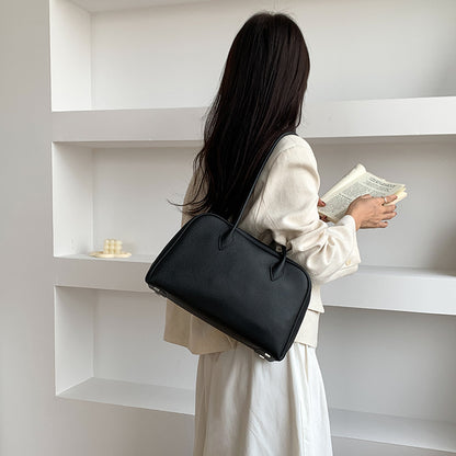 Black leather shoulder bag shown from the back while carried
