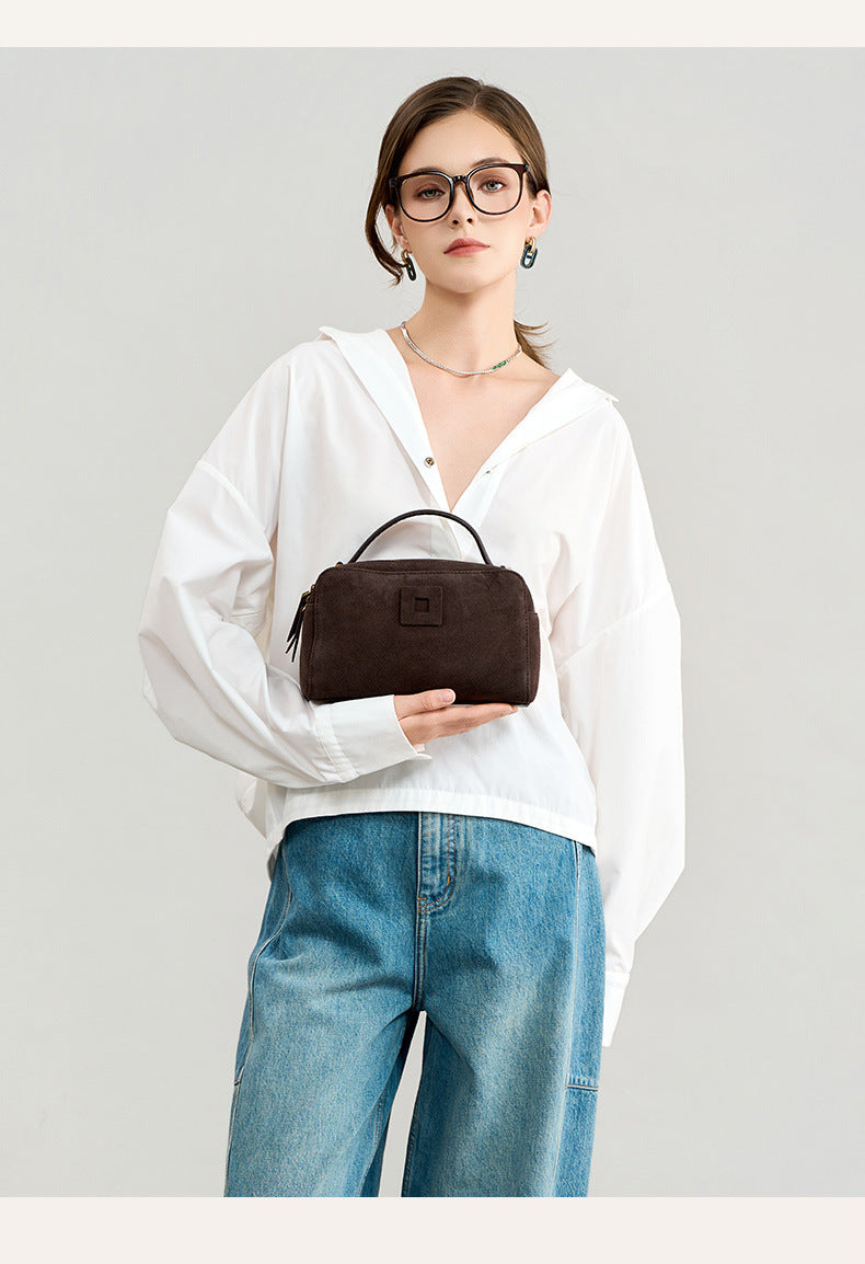 Front view of the compact crossbody bag held by a model
