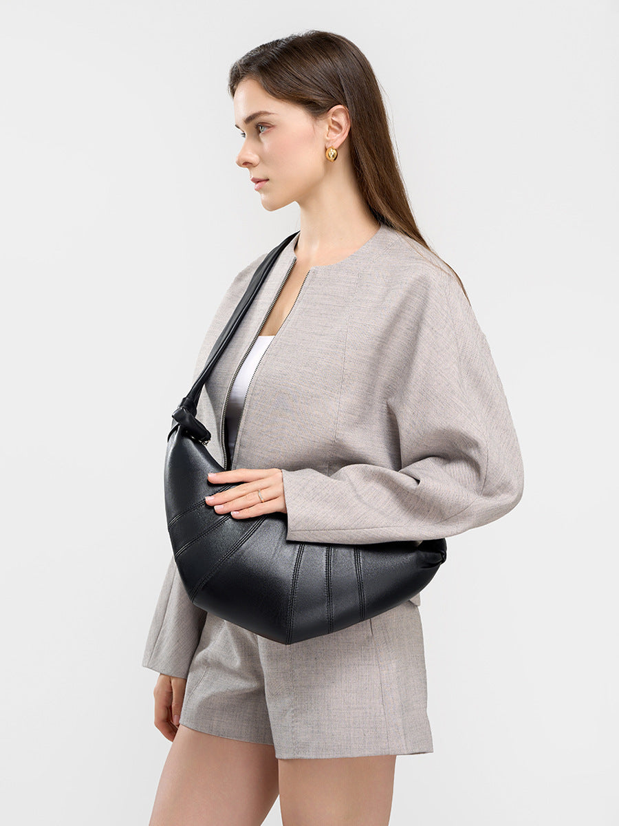 Model carrying black crescent bag under the arm in casual gray outfit