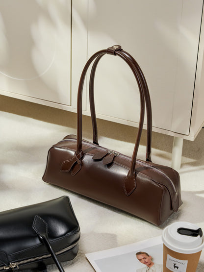 Coffee leather baguette bag styled on floor with accessories