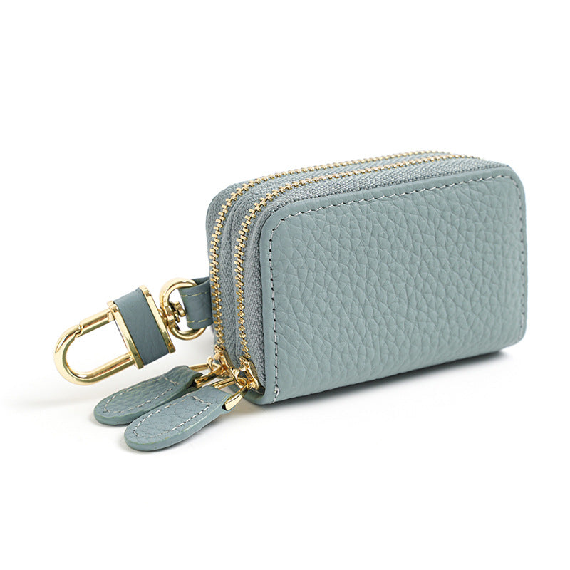 Light blue cowhide leather key case pouch with double zipper and gold-tone rotating clip on white background
