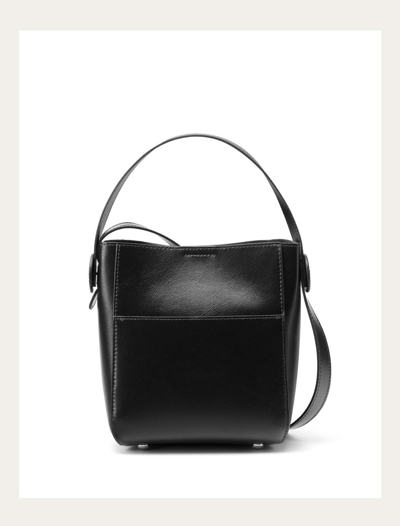 Black cowhide leather bucket bag with shoulder strap on plain white background