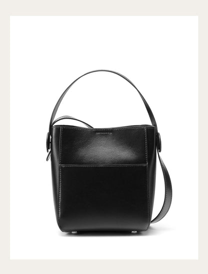 Black cowhide leather bucket bag with shoulder strap on plain white background