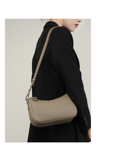 Model wearing taupe bag at hip on shoulder strap