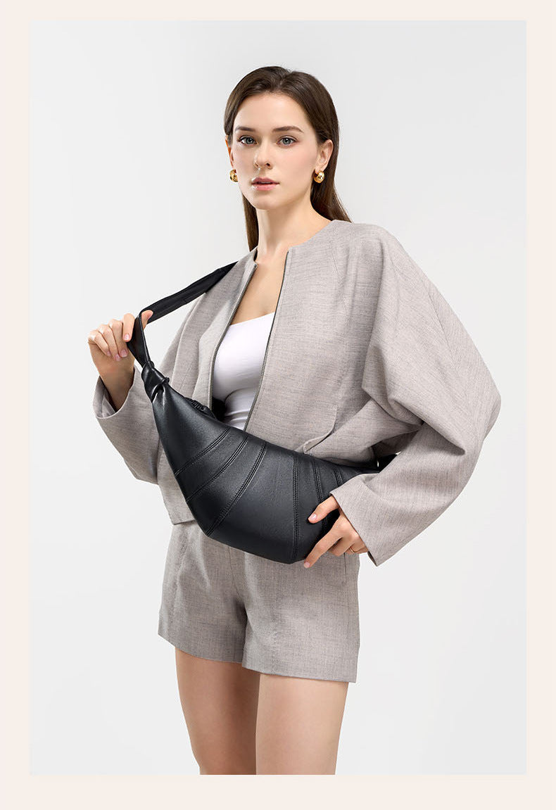 Front view of model holding black crescent bag at waist