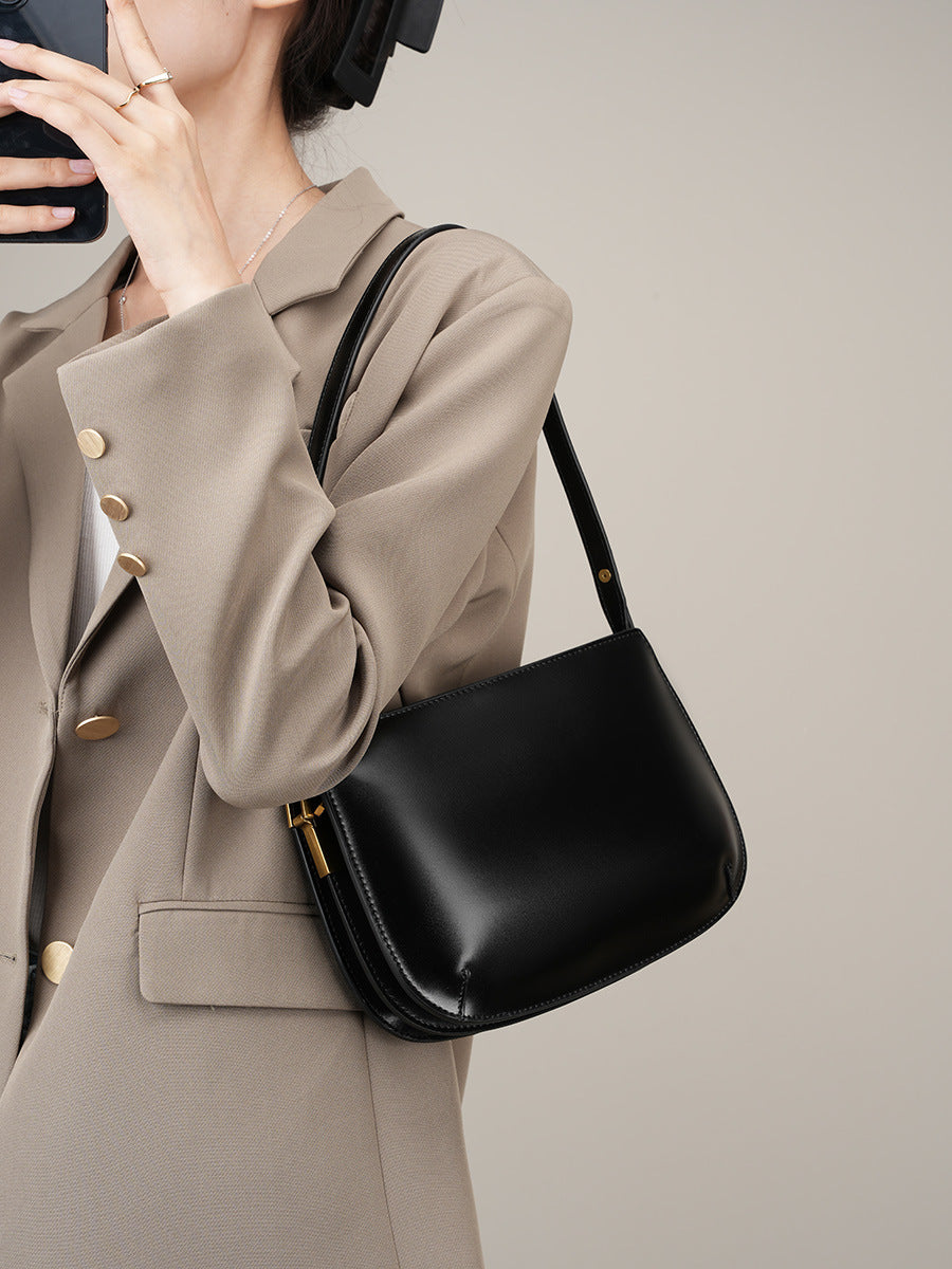 Model wearing a beige blazer carrying the black leather underarm bag on the shoulder