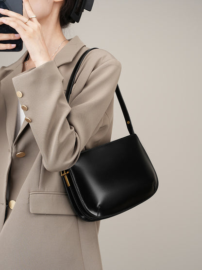 Model wearing a beige blazer carrying the black leather underarm bag on the shoulder