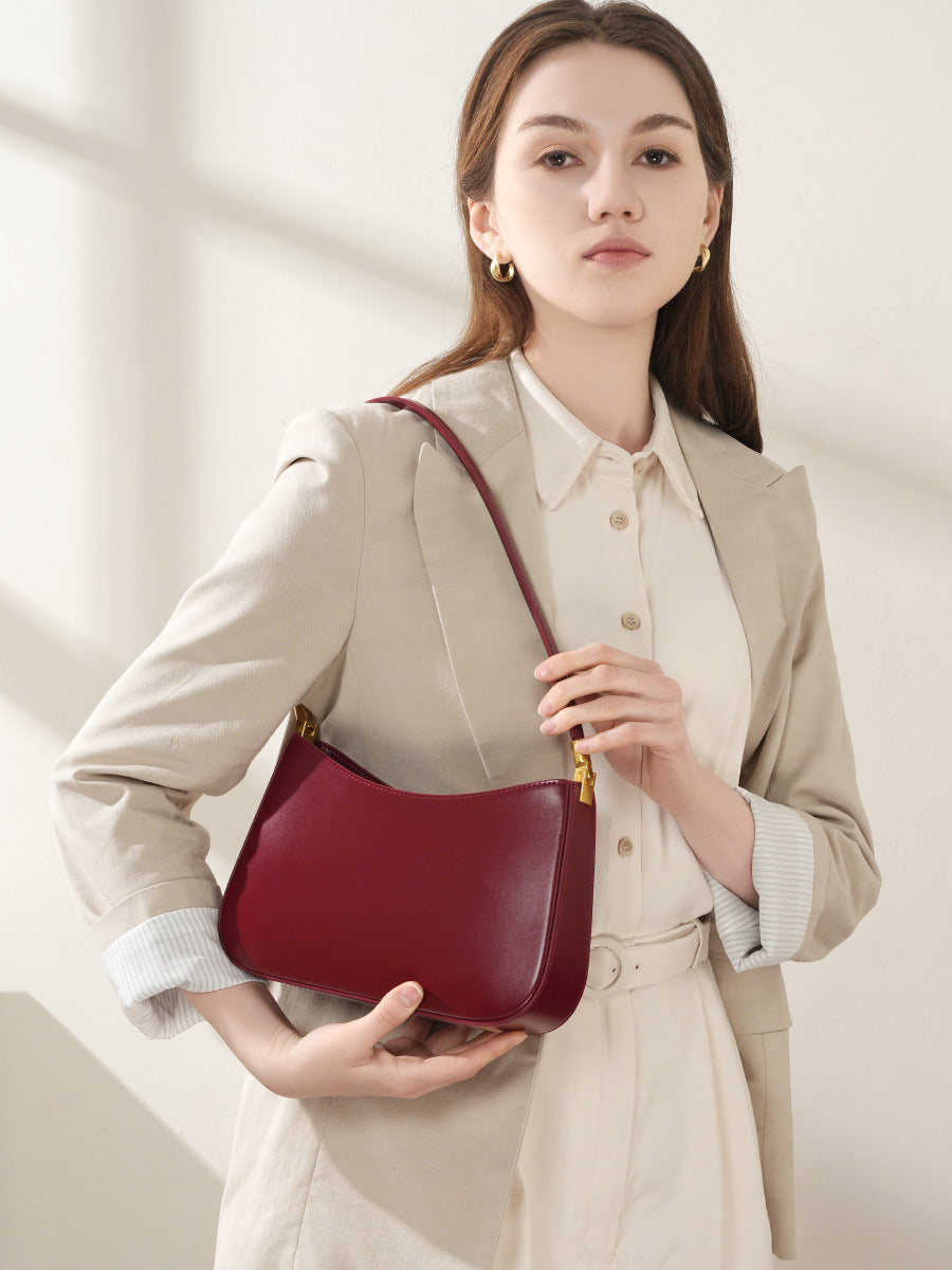 Wine red shoulder bag worn at the hip with strap over the shoulder