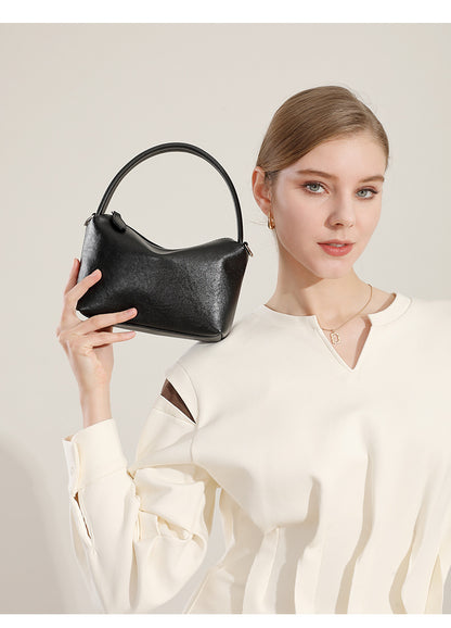 Black leather pillow bag held up close by a model