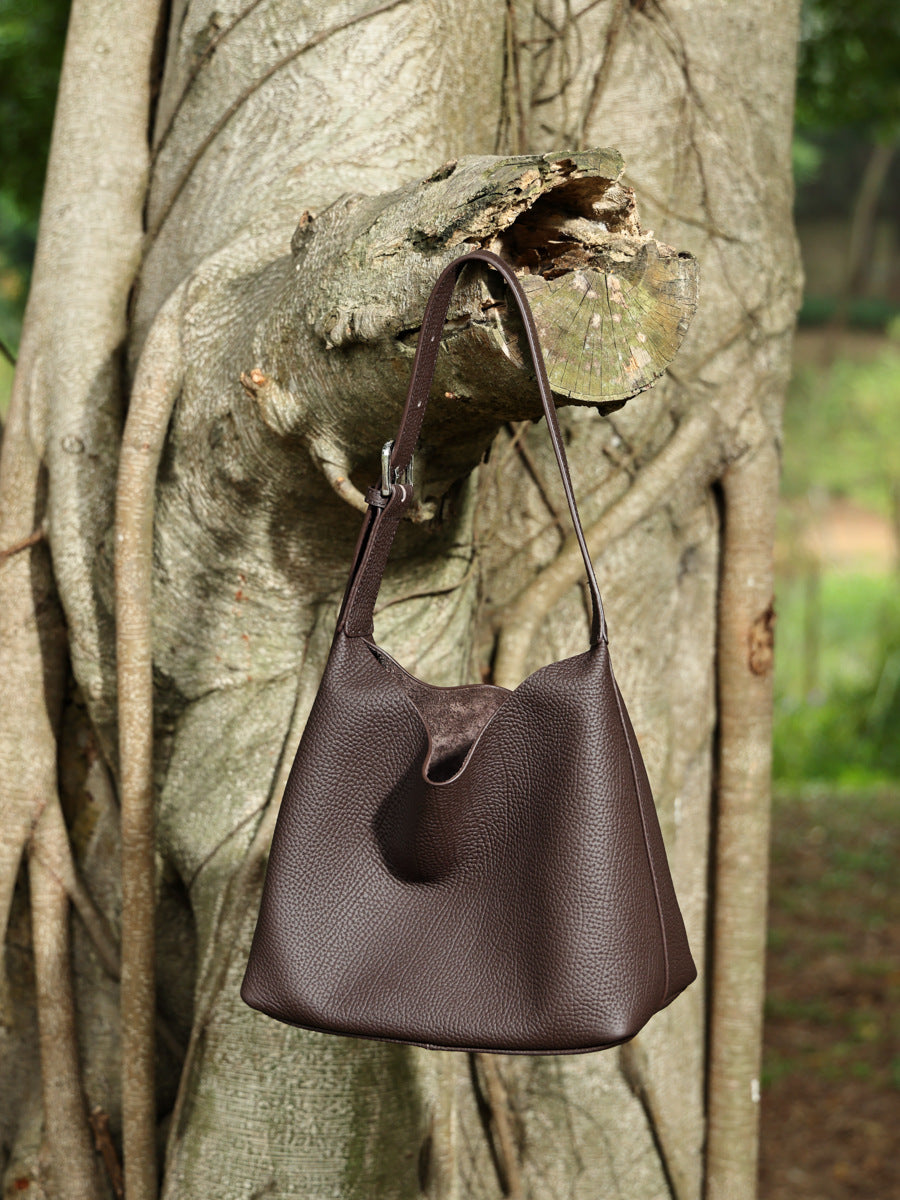 Coffee brown pebbled leather hobo bag displayed against a tree trunk