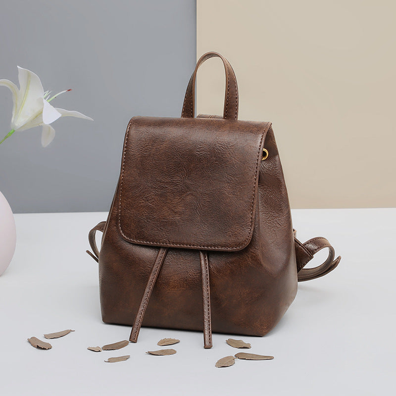 Front view of a vintage brown backpack with flap and drawstring