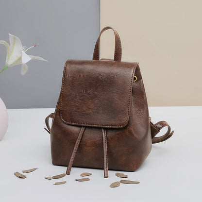 Front view of a vintage brown backpack with flap and drawstring
