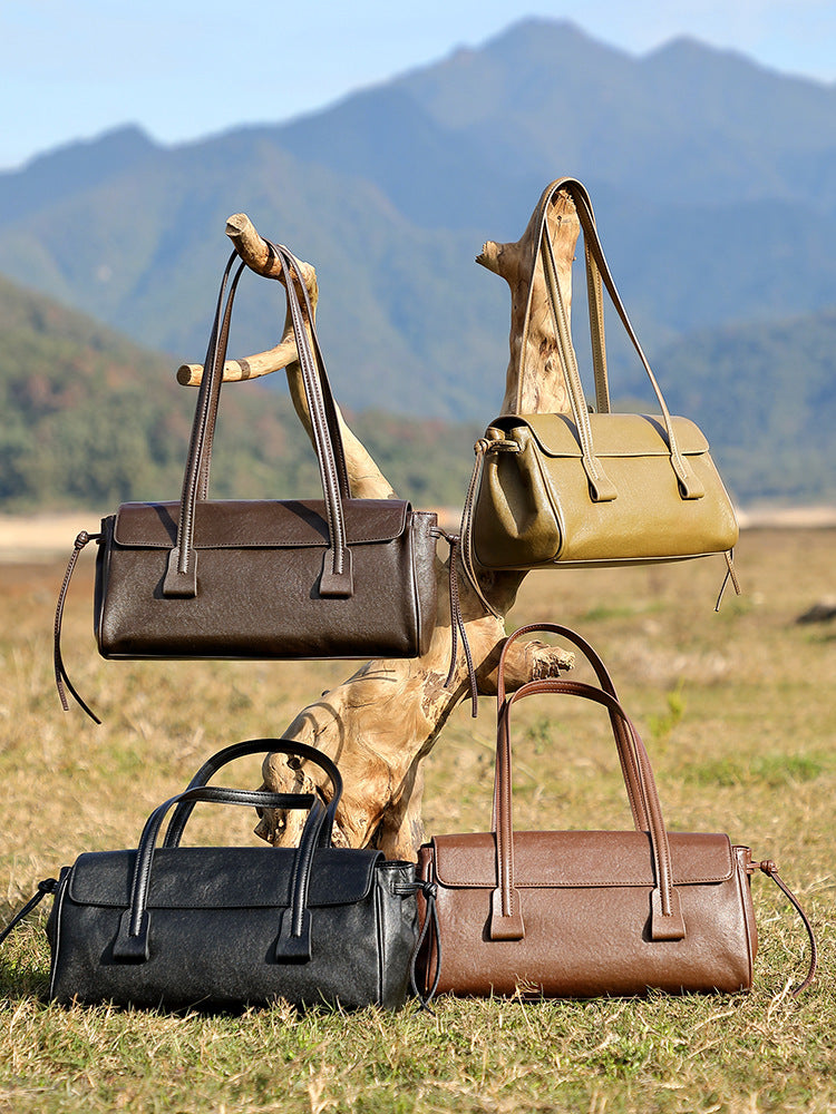 Four cowhide leather shoulder bags in coffee, olive, black, and brown displayed outdoors