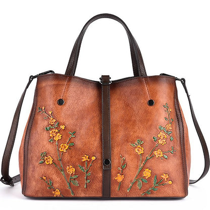 Front view of a vintage brown leather tote with floral detailing and shoulder strap