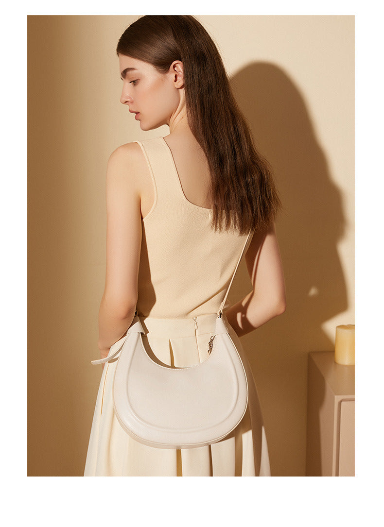 Back view of a cream white crescent crossbody bag in soft natural light
