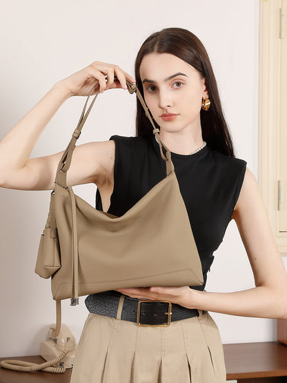 Model holding gray cowhide leather hobo shoulder bag by the strap