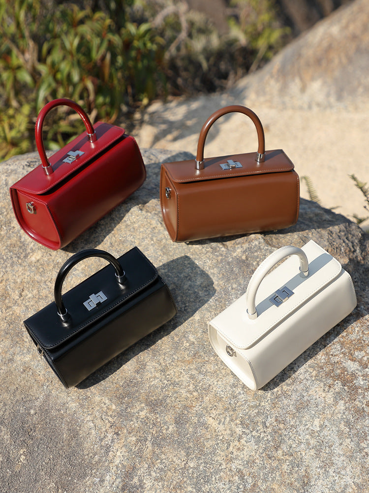 All four colorways of the box handbag arranged on a stone surface
