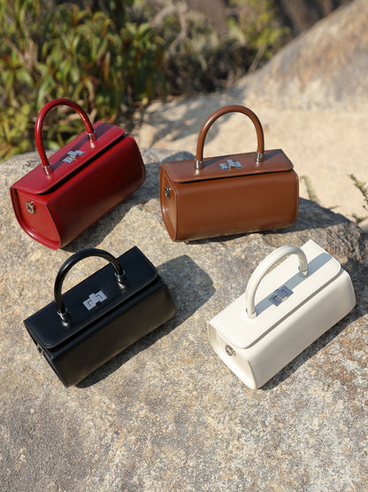All four colorways of the box handbag arranged on a stone surface