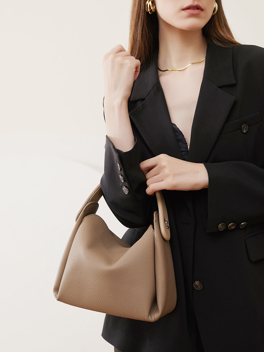 Woman in black blazer carrying milk tea leather shoulder bag
