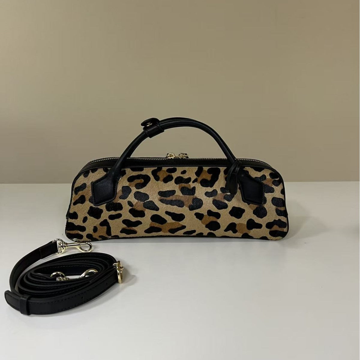 Brown leopard bag and detached black strap arranged for display