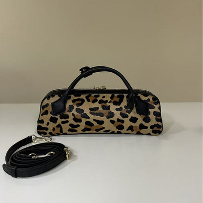 Brown leopard bag and detached black strap arranged for display
