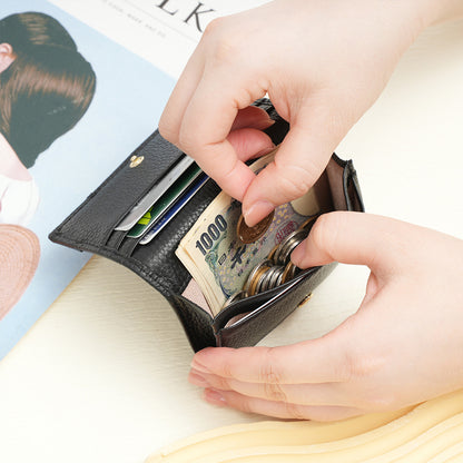 Black cowhide leather wallet being filled with cash and coins in hand