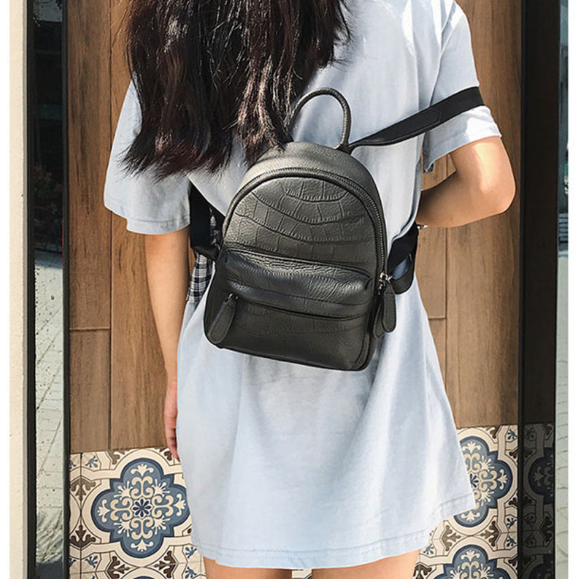 Black mini backpack worn on the back