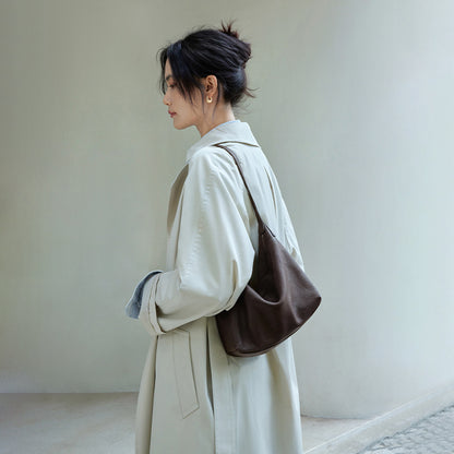 Brown leather hobo shoulder bag worn with a light coat, side view