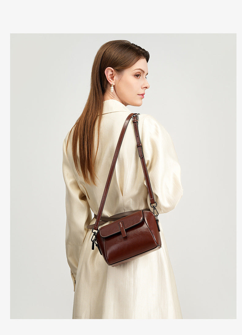 Model in cream silk dress carrying a brown crossbody bag at her side