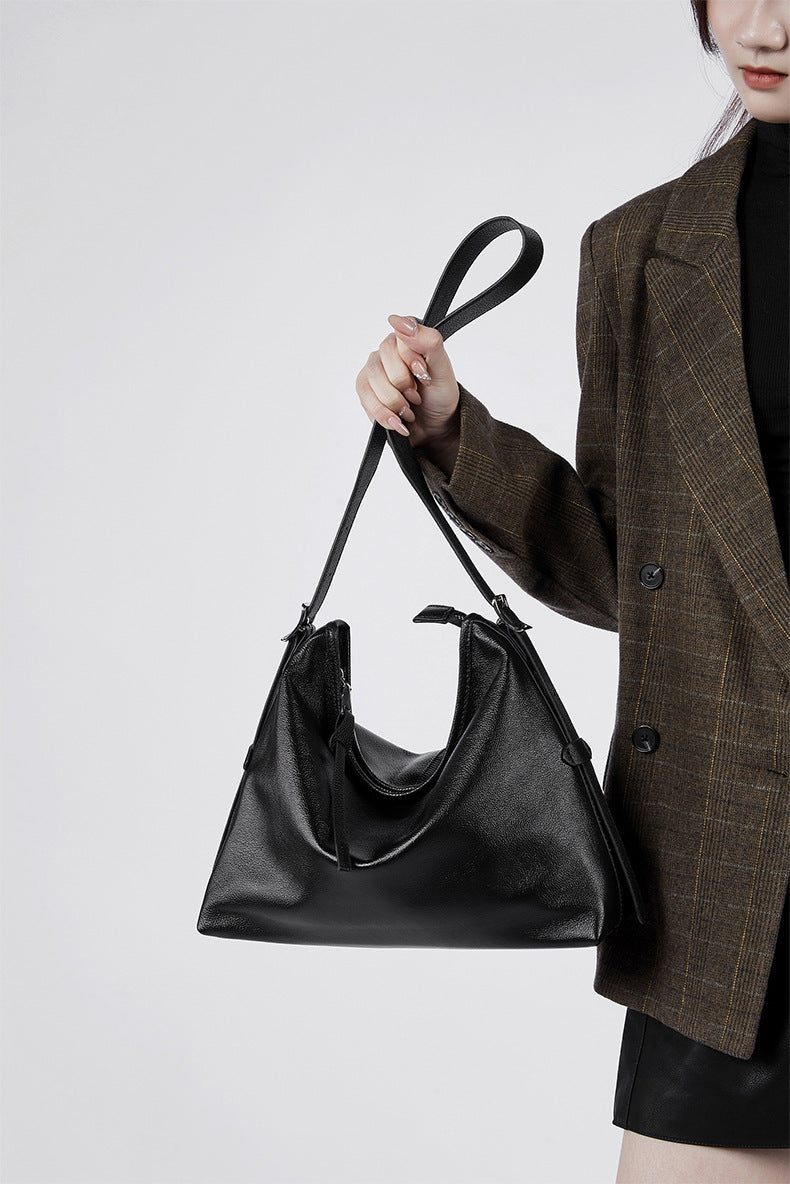Hand holding a black leather shoulder bag
