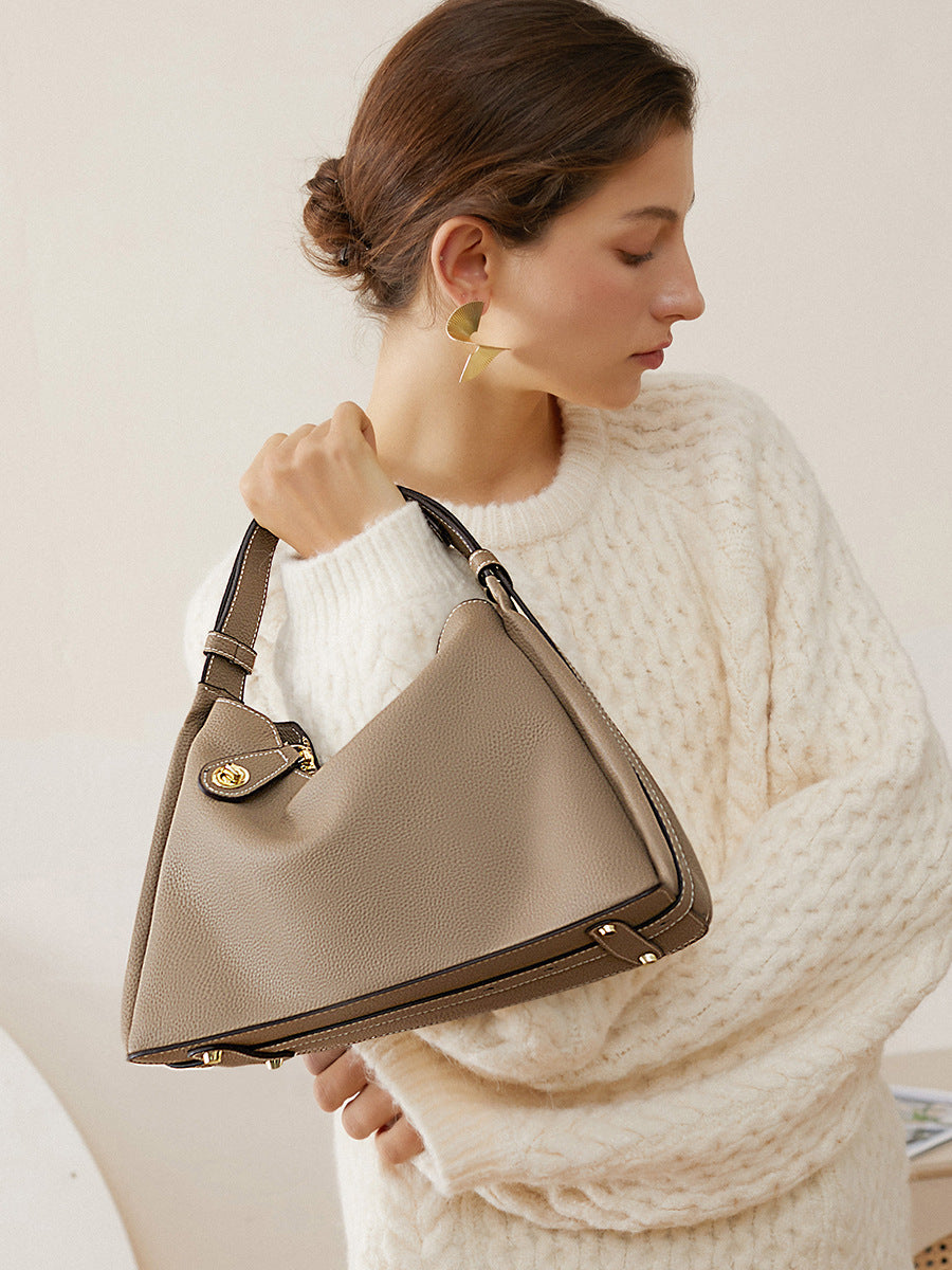 Model carrying dark gray cowhide leather shoulder bag in cream knit sweater