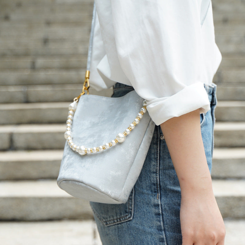 Silver gray split leather mini bucket bag worn crossbody on stone steps