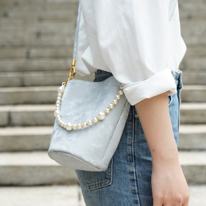 Silver gray split leather mini bucket bag worn crossbody on stone steps
